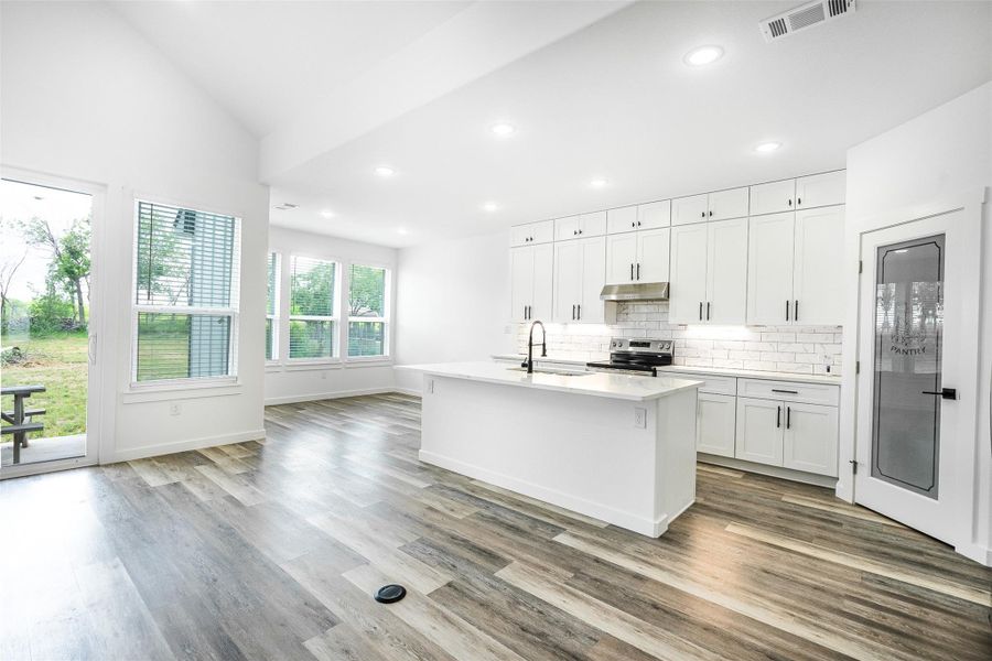 A well-lit kitchen boasts a large island with sink, perfect for culinary endeavors and entertaining. A well-lit kitchen boasts a large island with sink, perfect for culinary endeavors and entertaining.