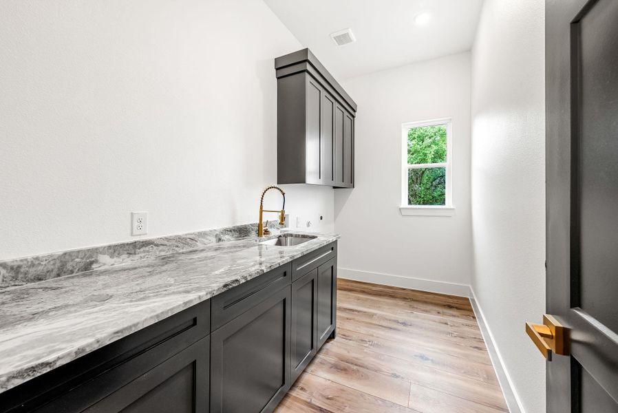 A well-appointed laundry room features ample counter space, built-in cabinetry, and practical wood flooring.