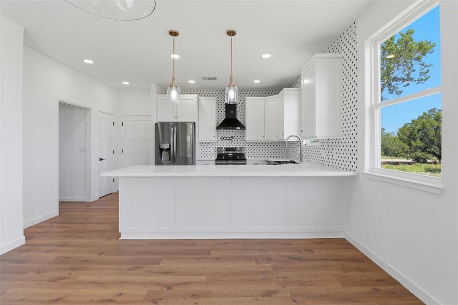 Kitchen featuring white shaker cabinetry, stainless steel appliances, a tile backsplash with a geometric pattern, and pendant lighting Kitchen featuring white shaker cabinetry, stainless steel appliances, a tile backsplash with a geometric pattern, and pendant lighting