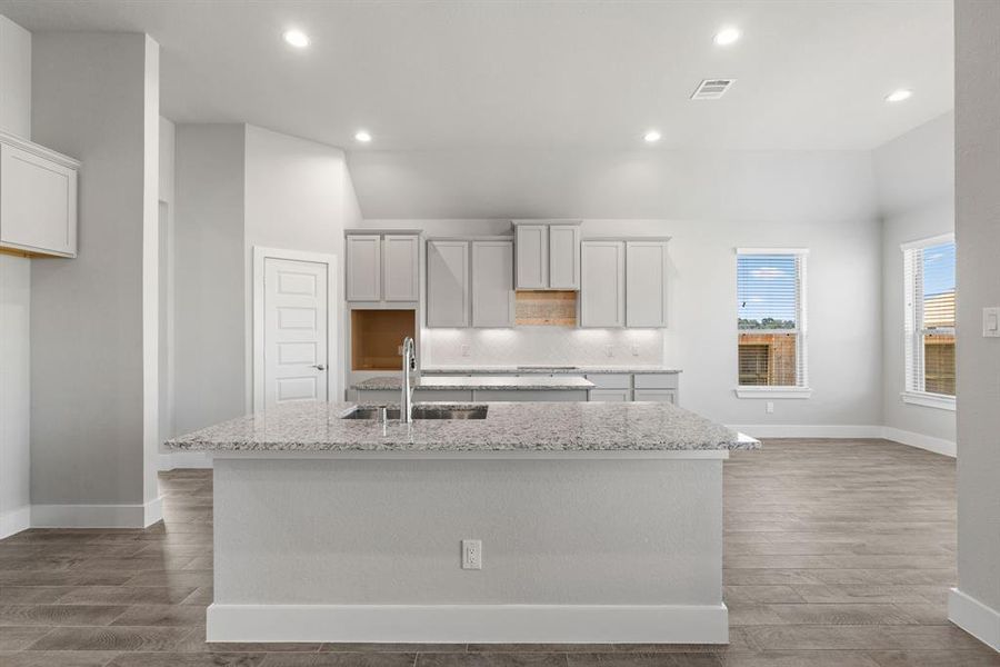 Culinary haven, featuring granite countertops, a tile backsplash, stainless steel appliances (to be installed), and 42” upper cabinets. Sample photo of completed home with similar floor plan. As-built interior colors and selections may vary.