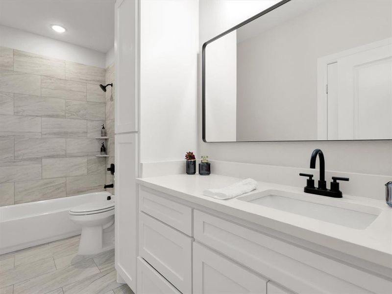 Full bathroom featuring vanity, tiled shower / bath combo, and toilet