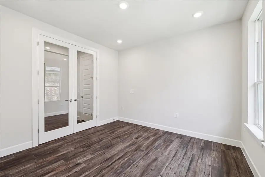 Empty room featuring dark wood-style floors, french doors, and recessed lighting