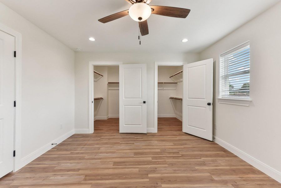 Primary bedroom with 2 walk in closets, baseboards, recessed lighting.