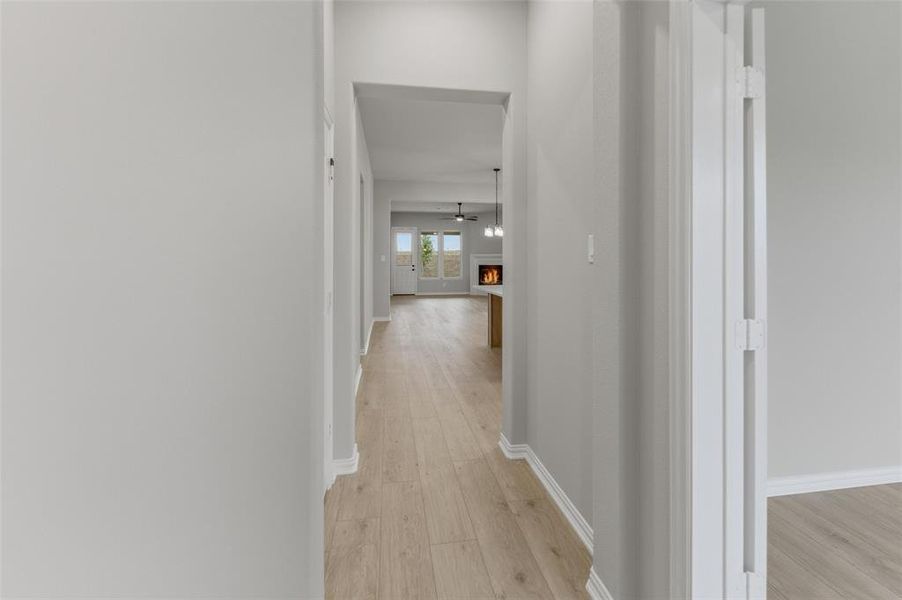 Hallway featuring light wood-finish flooring, white baseboards, and neutral wall tones