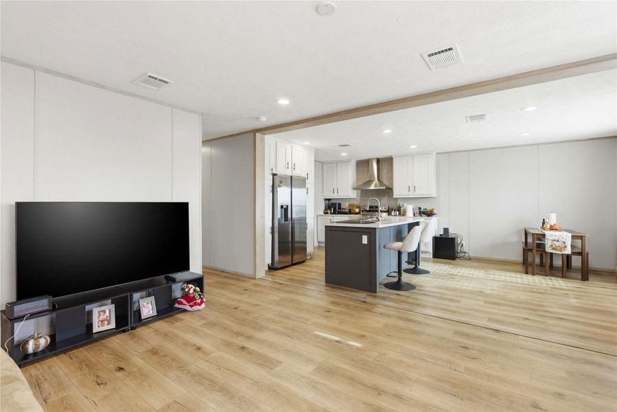 An open-concept layout showcases the integrated kitchen and living area with continuous wood flooring.