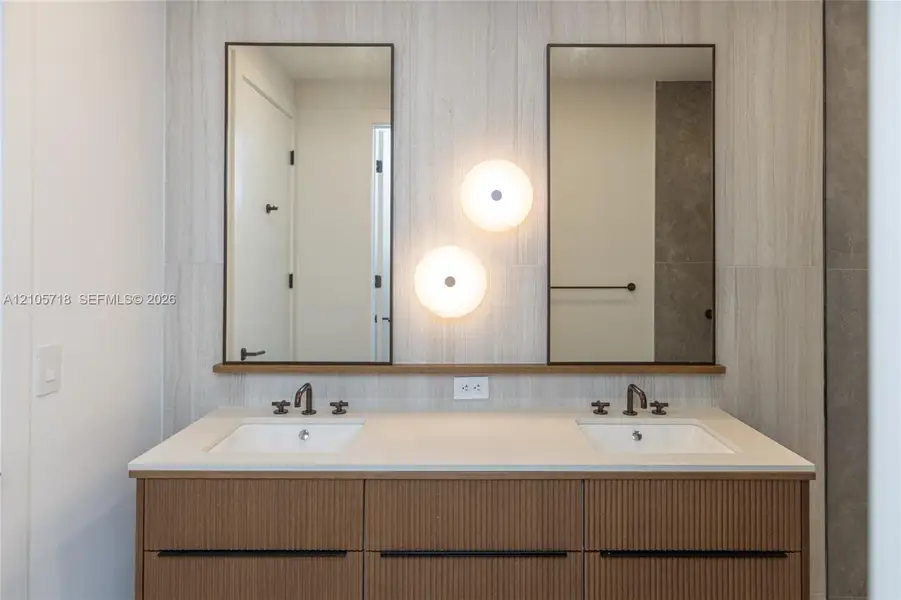 Master bath Double vanity with a textured wood-finish cabinet, stone-finish countertop, dual rectangular undermount sinks, bronze-finish widespread faucets, and twin rectangular mirrors