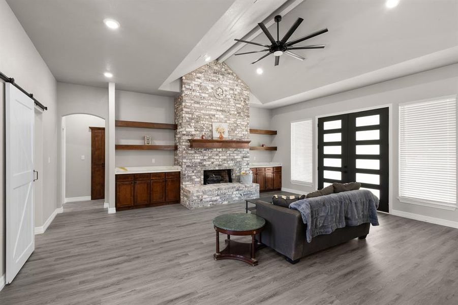 Living room featuring a barn door, arched walkways, light wood finished floors, a fireplace, and recessed lighting