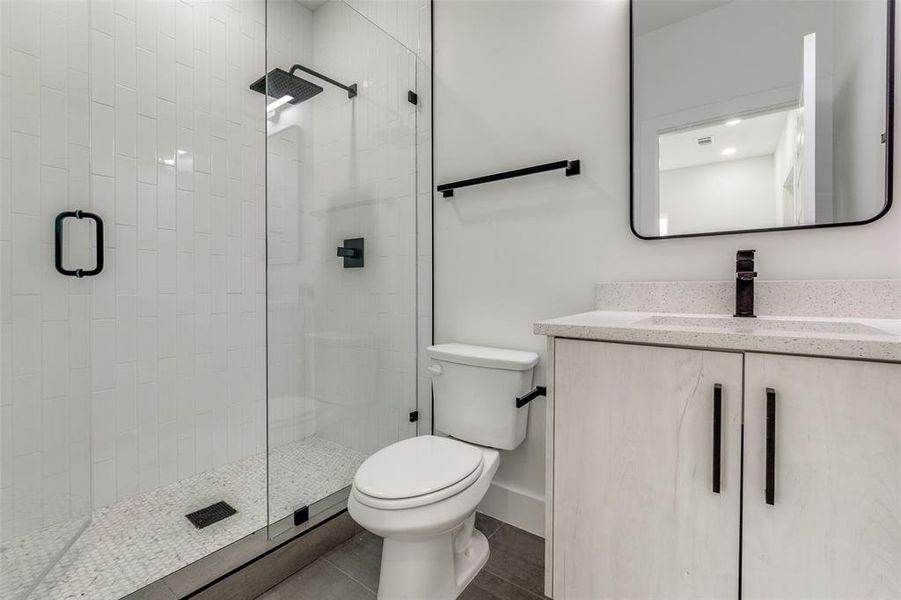 Bathroom with vanity, toilet, and a stall shower