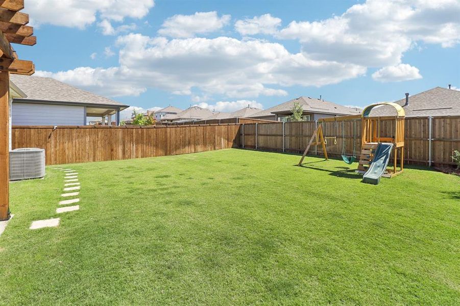 Fenced backyard featuring a playground and a residential view Fenced backyard featuring a playground and a residential view