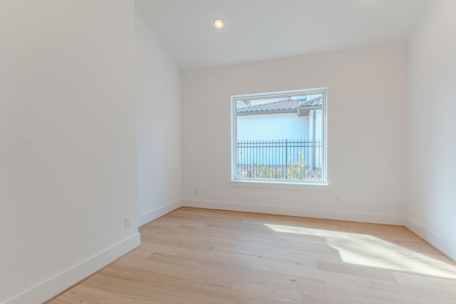 This room features a bright, airy space with light wood flooring and neutral walls. A large window allows for natural light and offers a view of the outdoor area. Ideal for a bedroom or home office.