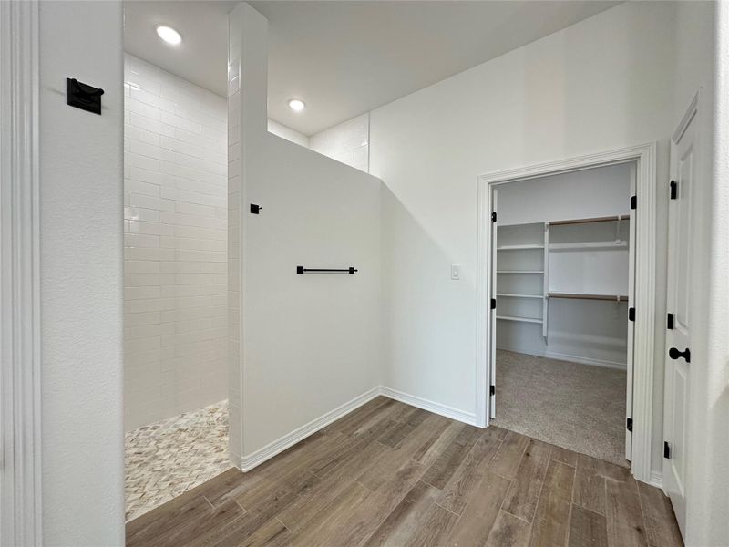 Bathroom featuring a walk in closet, walk in shower, wood tiled floors, and recessed lighting