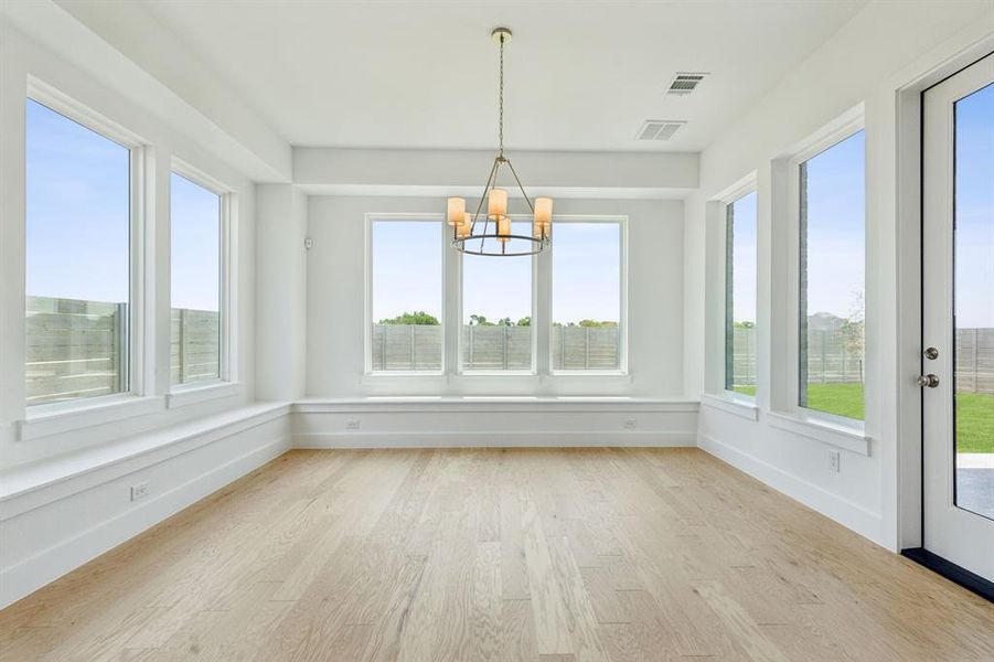 Spacious room featuring light wood-finish flooring, white walls, and an array of large windows Spacious room featuring light wood-finish flooring, white walls, and an array of large windows