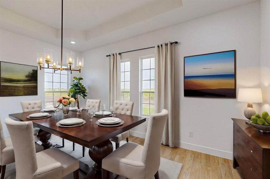 Vistual Staged Dining area with light hardwood / wood-style floors, a raised ceiling, and a chandelier