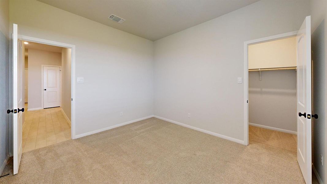 Unfurnished bedroom featuring a walk in closet and light colored carpet Unfurnished bedroom featuring a walk in closet and light colored carpet