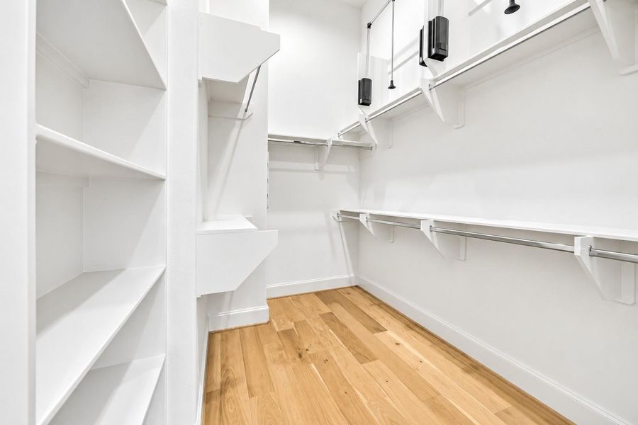LARGE walk-in closet in the primary suite features extra shelving and drop-down space-saving closet rods.