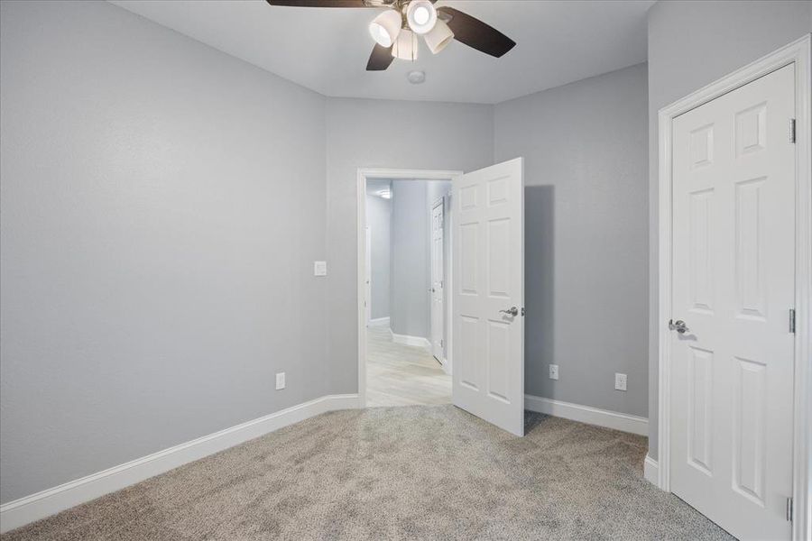 Secondary bedroom featuring ceiling fan and light colored carpet