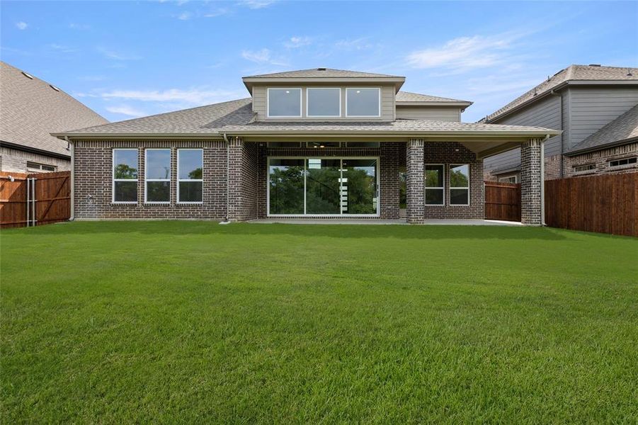 Back of house with roof with shingles, brick siding, a fenced backyard, and a lawn Back of house with roof with shingles, brick siding, a fenced backyard, and a lawn