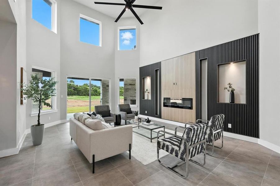 Living area with a high ceiling, ceiling fan, and plenty of natural light