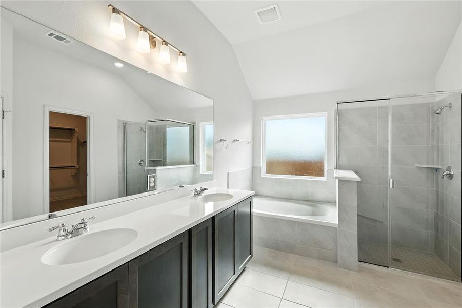 Full bathroom with a stall shower, a spacious closet, a garden tub, double vanity, and lofted ceiling Full bathroom with a stall shower, a spacious closet, a garden tub, double vanity, and lofted ceiling