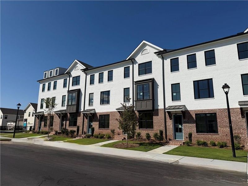 White brick and brick veneer exterior featuring dark-framed windows, a dormer, and a covered entryway