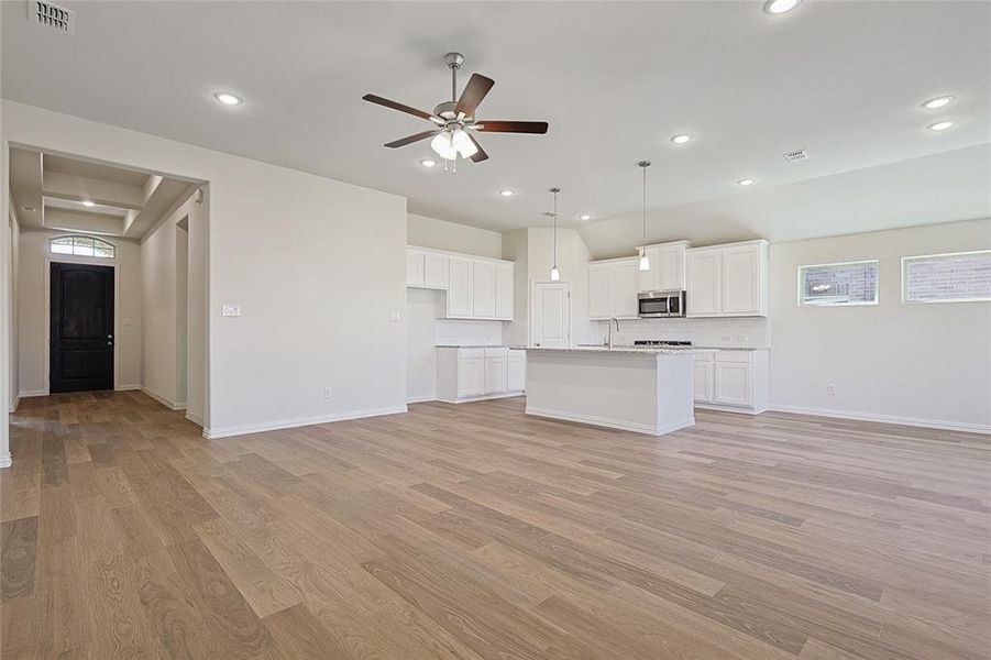 Unfurnished living room with sink, light hardwood / wood-style floors, and ceiling fan