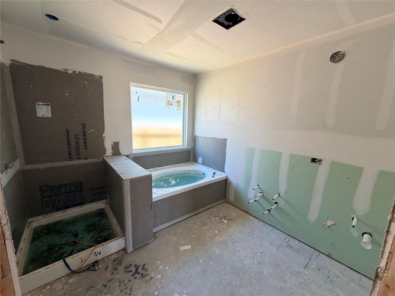 A well-lit primary bathroom featuring a soaking tub and a separate shower enclosure.
