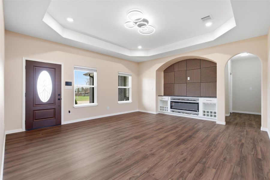 Entryway featuring dark wood-style flooring, arched walkways, recessed lighting, and a raised ceiling