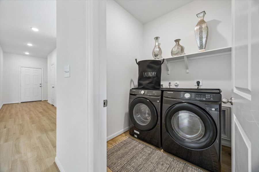 Laundry room with light wood-type flooring, washing machine and clothes dryer, and recessed lighting