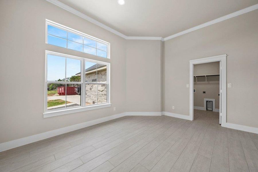 Empty room featuring ornamental molding, light wood finished floors, and baseboards Empty room featuring ornamental molding, light wood finished floors, and baseboards