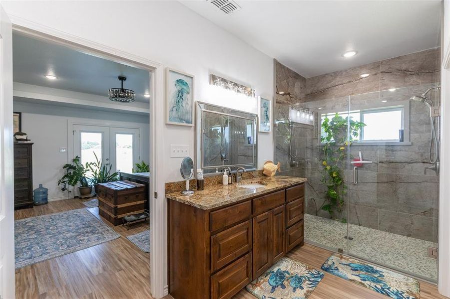 Bathroom featuring a wood-finish vanity with a granite countertop, undermount sink, and a framed mirror Bathroom featuring a wood-finish vanity with a granite countertop, undermount sink, and a framed mirror