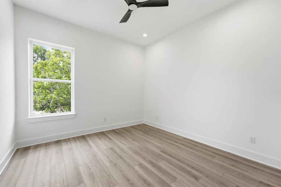 Peaceful, private, and filled with natural light. This secondary bedroom with a large window framing mature tree views, recessed lighting, and a modern ceiling fan is the kind of room that makes waking up easy. Peaceful, private, and filled with natural light. This secondary bedroom with a large window framing mature tree views, recessed lighting, and a modern ceiling fan is the kind of room that makes waking up easy.