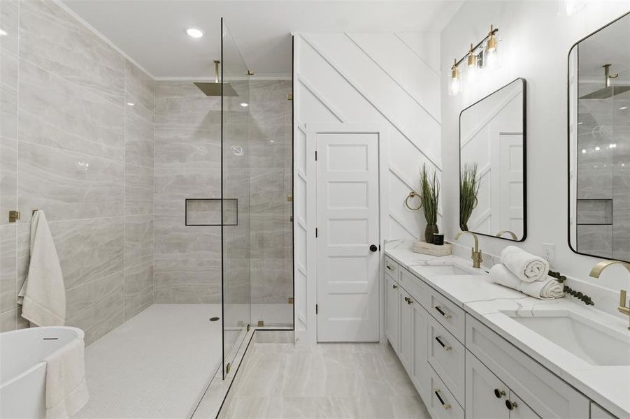 Contemporary bathroom featuring a spacious walk-in shower with a built-in niche and rainfall showerhead, dual vanities with undermount sinks, stone countertops, and gold-finish fixtures