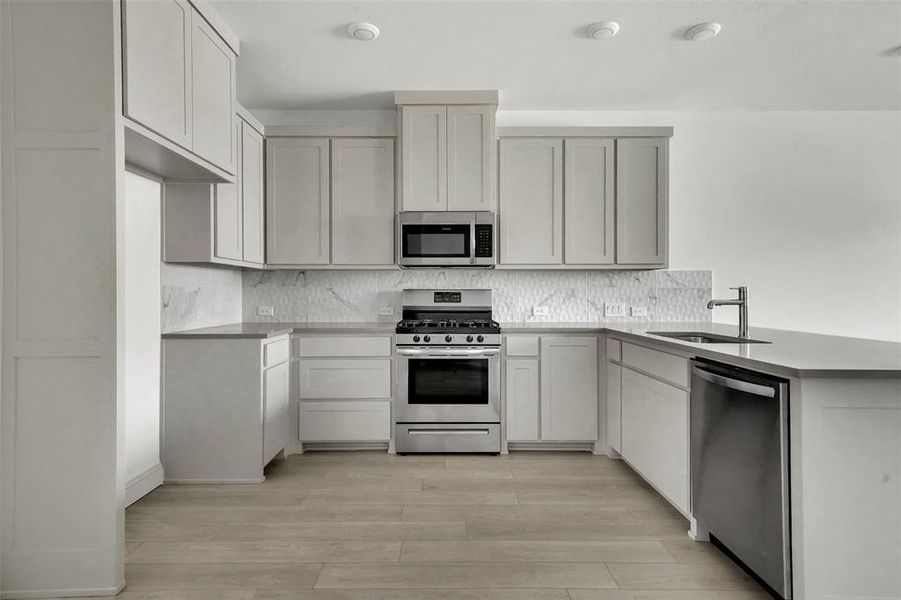 Kitchen with stainless steel appliances, a peninsula, tasteful backsplash, light stone countertops, and light wood-style floors Kitchen with stainless steel appliances, a peninsula, tasteful backsplash, light stone countertops, and light wood-style floors