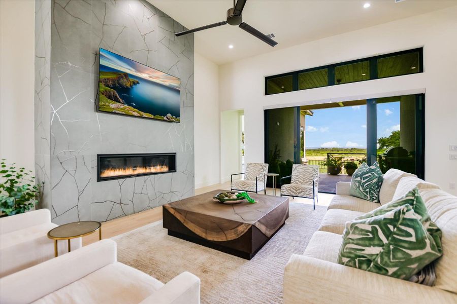 A striking fireplace wall complements a light-filled interior, seamlessly connected to an outdoor vista through wide glass doors.