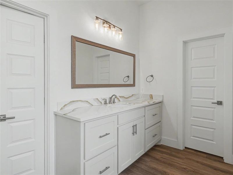 Contemporary vanity featuring a dual-sink countertop with an integrated backsplash, shaker-style cabinetry, and brushed nickel hardware