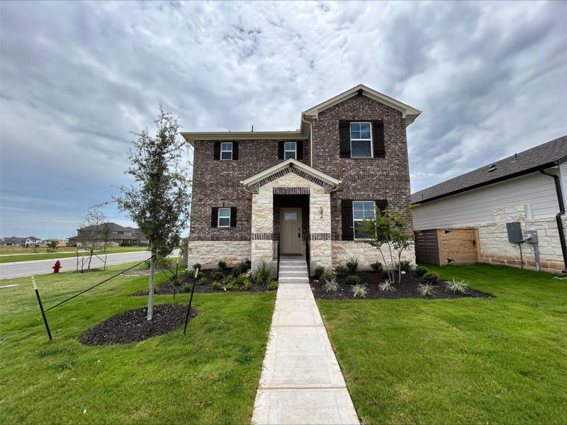 View of front of property featuring a front yard, brick siding, and stone siding View of front of property featuring a front yard, brick siding, and stone siding