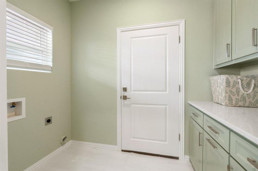 Clothes washing area featuring cabinets, light tile patterned floors, electric dryer hookup, and washer hookup