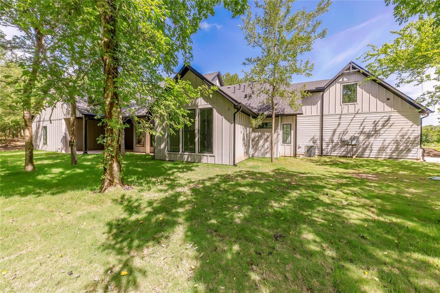 Rear view of property featuring board and batten siding, a lawn, and a shingled roof