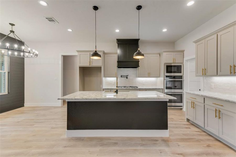 Kitchen featuring light stone countertops, pendant lighting, light wood-style floors, and recessed lighting Kitchen featuring light stone countertops, pendant lighting, light wood-style floors, and recessed lighting