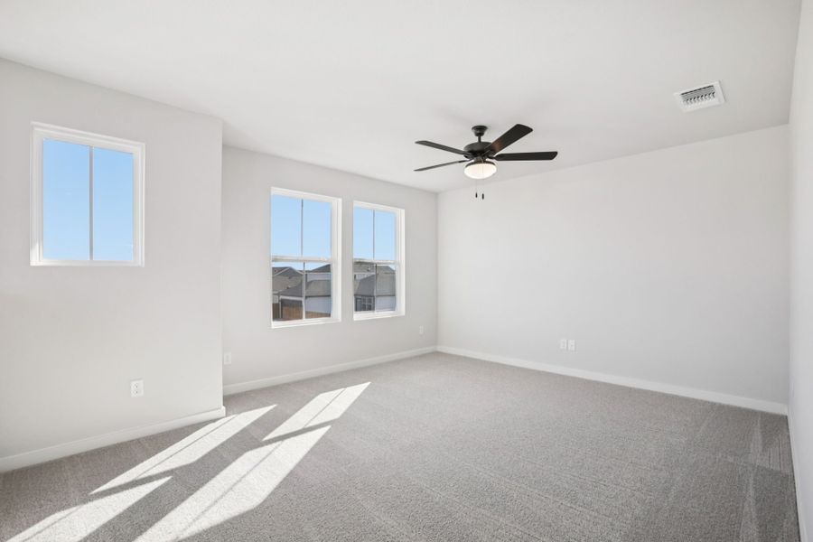 A room with a ceiling fan and windows.