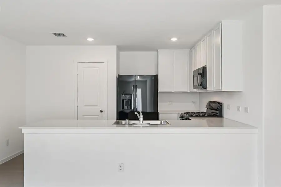 Kitchen featuring black appliances, a peninsula, recessed lighting, white cabinets, and light countertops