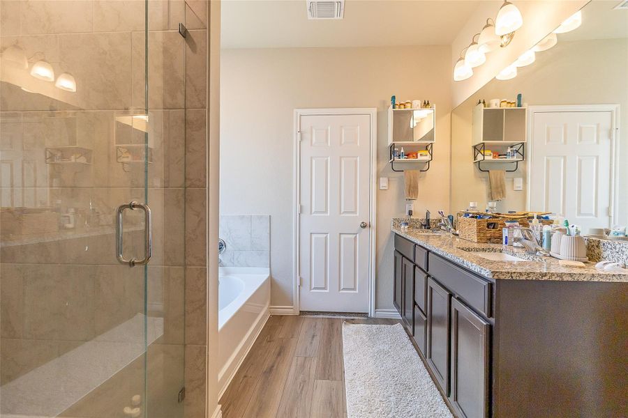 A well-appointed bathroom offers a separate shower, deep soaking tub, and a spacious double vanity with granite counters. A well-appointed bathroom offers a separate shower, deep soaking tub, and a spacious double vanity with granite counters.