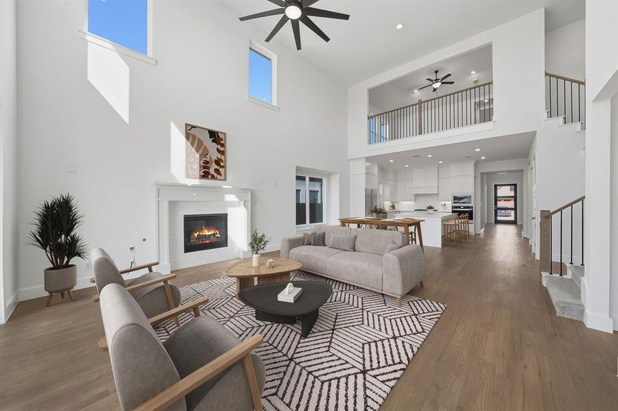 Living room featuring ceiling fan, a glass covered fireplace, wood finished floors, recessed lighting, and stairs Living room featuring ceiling fan, a glass covered fireplace, wood finished floors, recessed lighting, and stairs