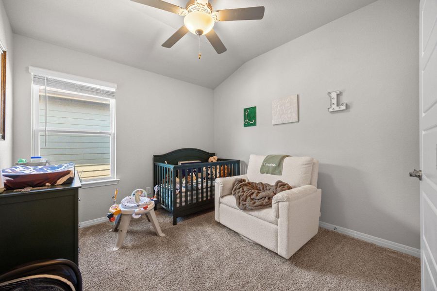Bedroom with carpet floors, a nursery area, lofted ceiling, and ceiling fan Bedroom with carpet floors, a nursery area, lofted ceiling, and ceiling fan