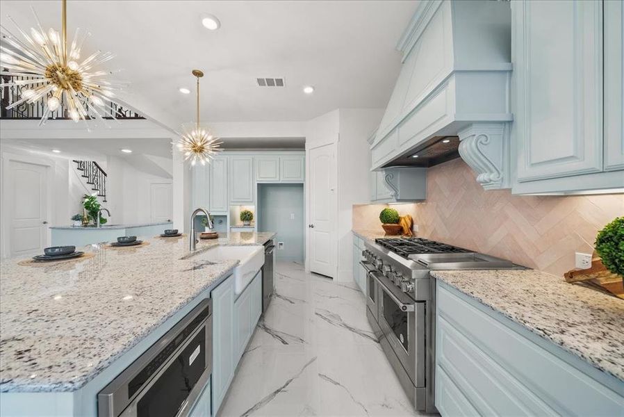 Kitchen with stainless steel appliances, a chandelier, quartz countertops, light marble finish floors, and recessed lighting Kitchen with stainless steel appliances, a chandelier, quartz countertops, light marble finish floors, and recessed lighting