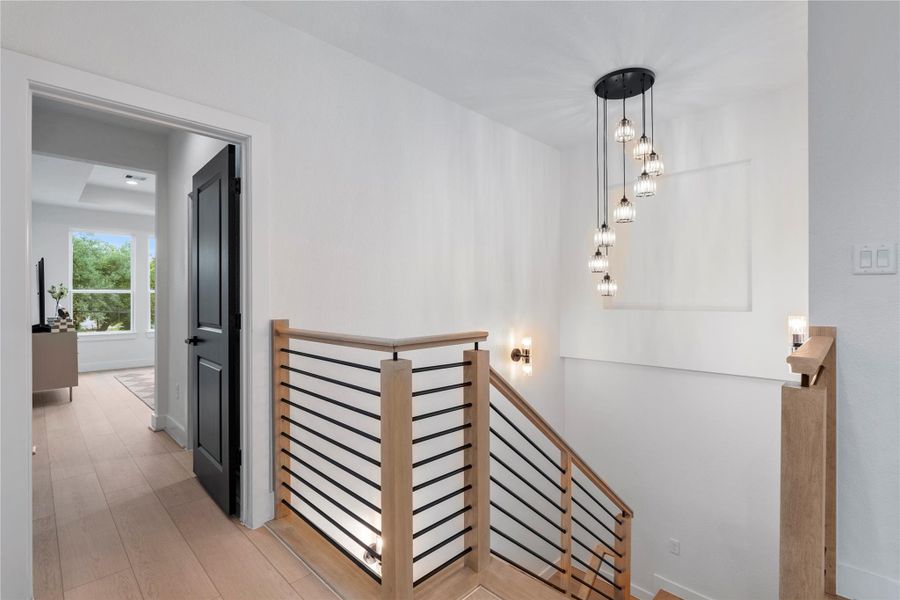 Staircase landing with modern railing detail and statement light fixture. Staircase landing with modern railing detail and statement light fixture.