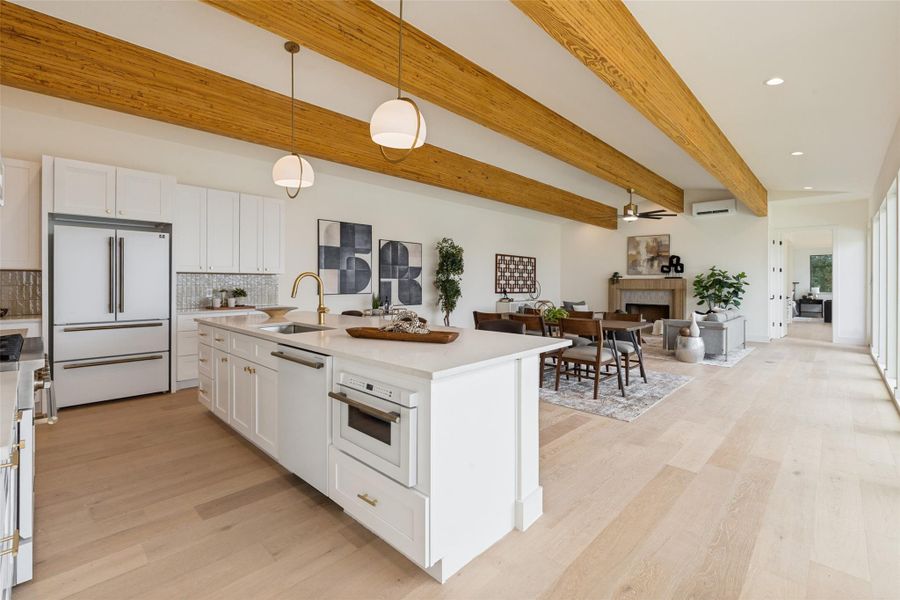 A grand chef's kitchen features a central island, gas range with pot filler and ample storage within crisp white cabinetry.
