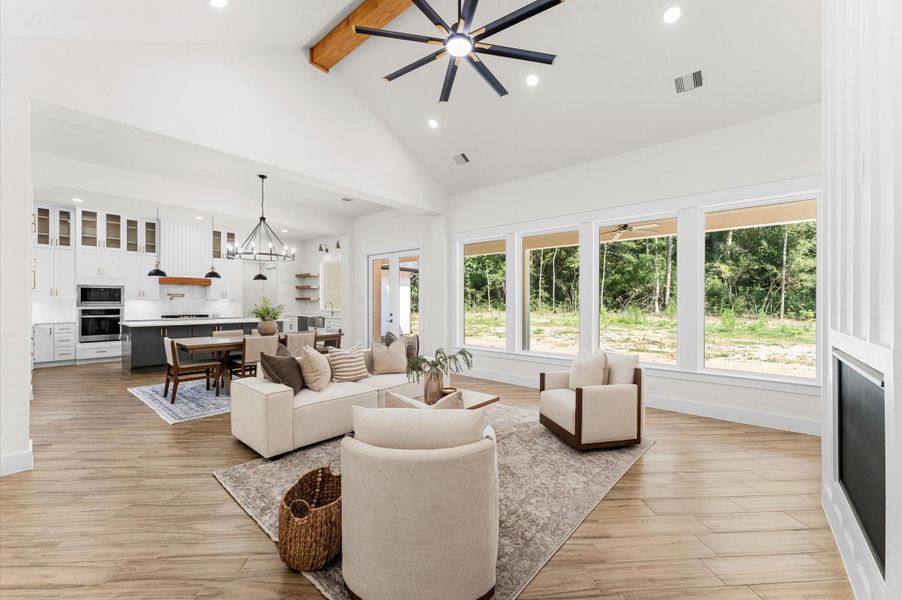 Grand living area with cathedral ceiling, cozy chimney, large windows for natural light, and open flow to the kitchen and dining—perfect for entertaining. Grand living area with cathedral ceiling, cozy chimney, large windows for natural light, and open flow to the kitchen and dining—perfect for entertaining.
