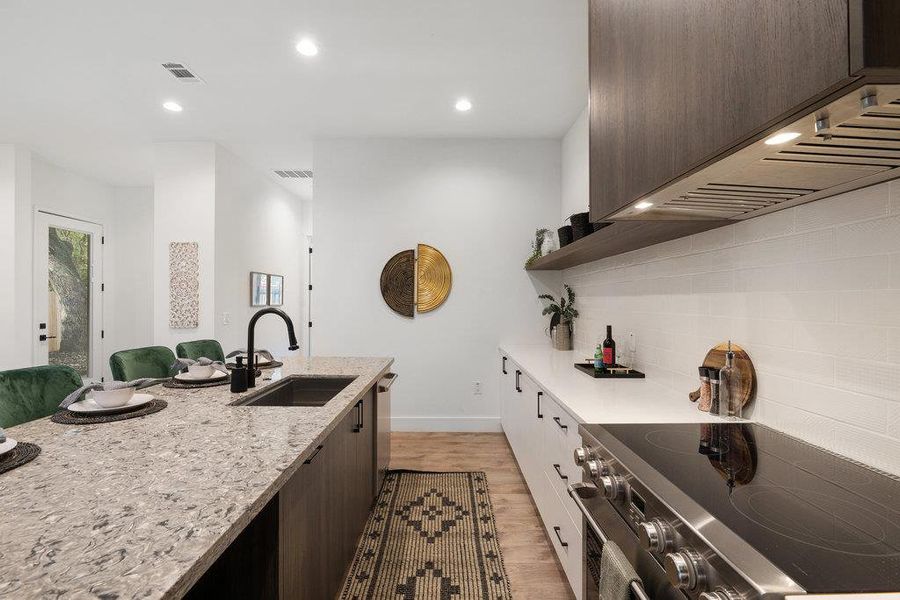 Kitchen featuring modern cabinets, dark brown cabinetry, light stone counters, stainless steel appliances, and recessed lighting