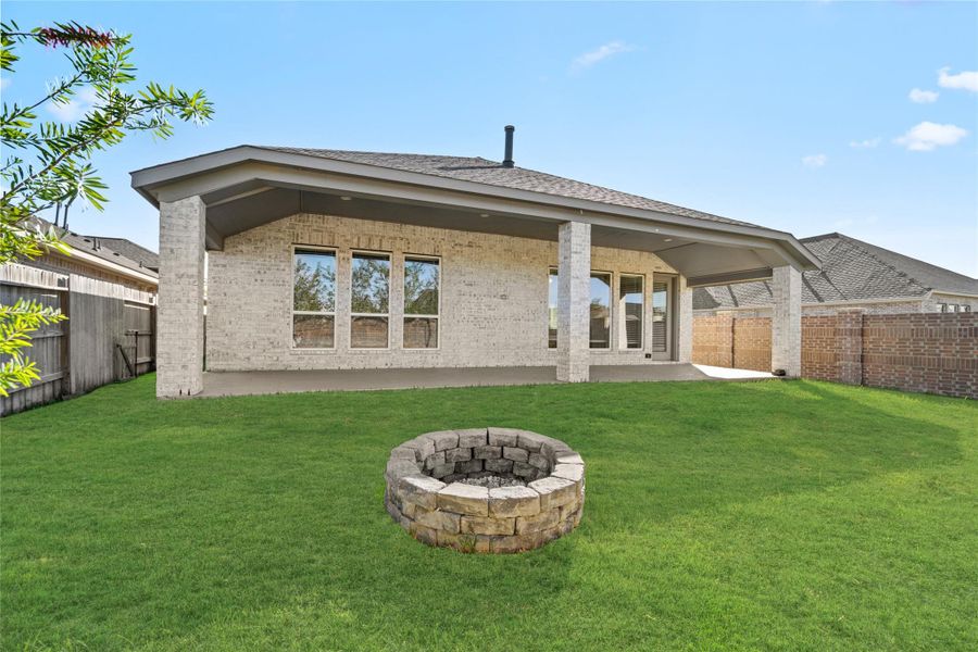 Private backyard featuring the covered patio and the cozy stone fire pit area.